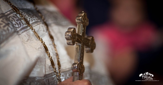 Clergy Member holding a large crucifix.